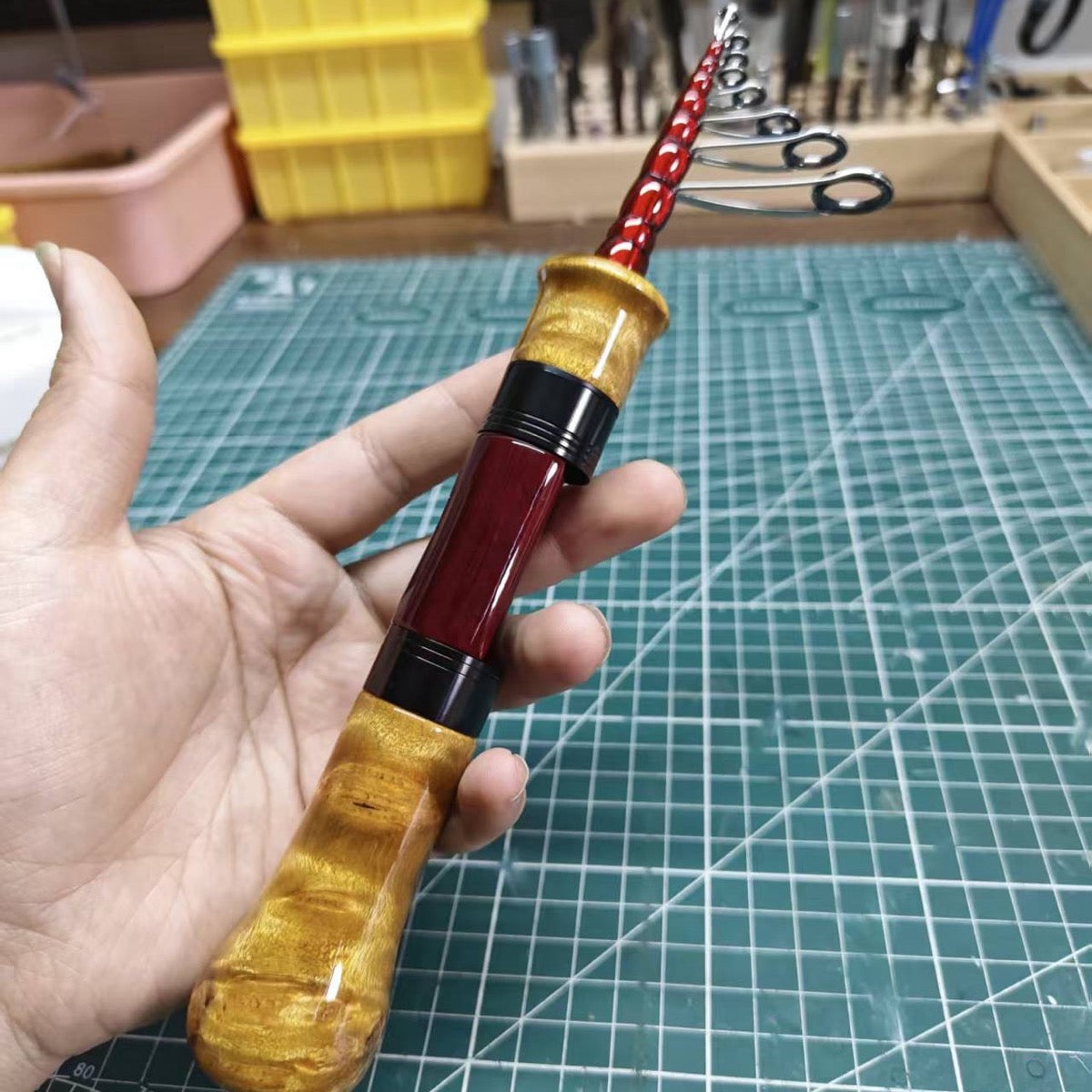 Handheld spinning travel rod example with a wood handle and red reel-seat insert.