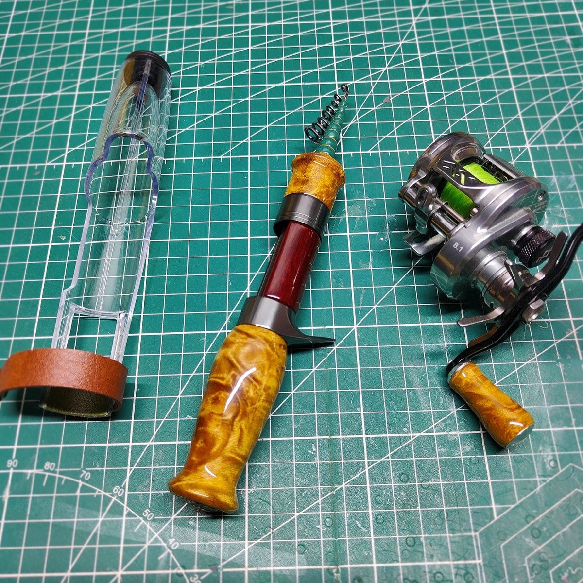 Collapsed Atelier Contour, clear protective cover and a separate casting reel on a work mat; reel not included.
