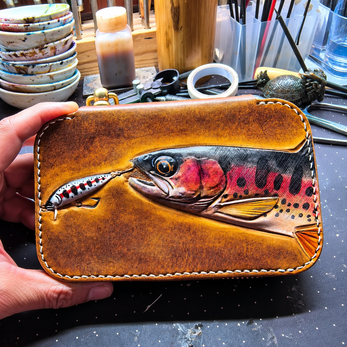 Spotted-fish and spoon artwork on a leather lure wallet
