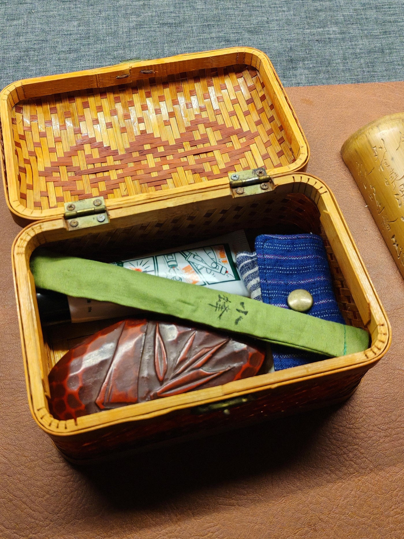 Open handmade bamboo tackle box holding small fishing cases and field accessories