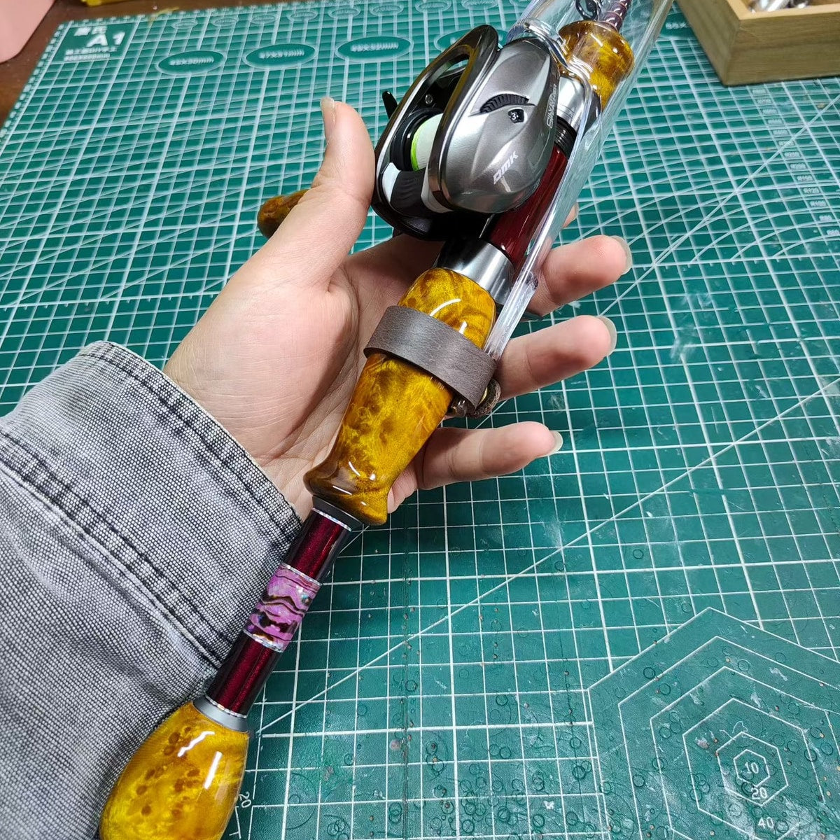 Atelier Contour extended-grip setup held in a hand with a casting reel mounted; reel not included.